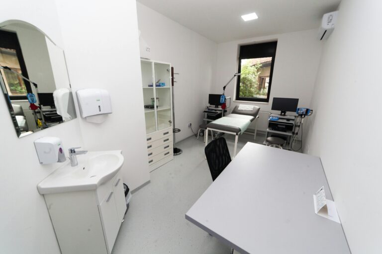 Clean and modern medical clinic room with diagnostic tools and furniture.